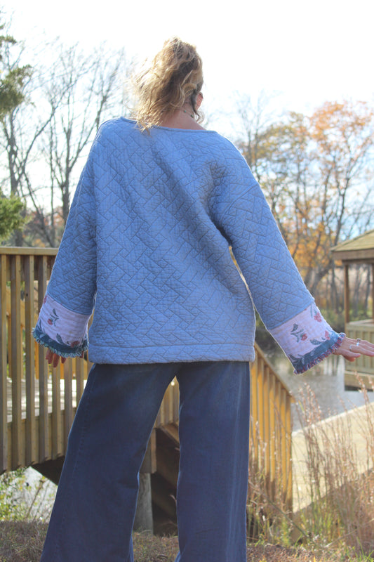 Upcycled blue quilted crewneck with patchwork fabric and floral fringe detail on the sleeves.