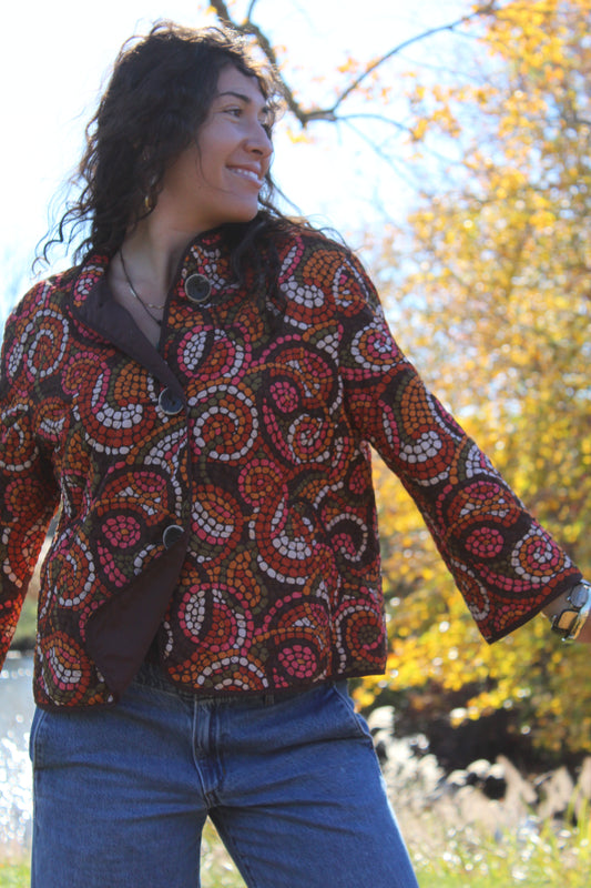 Thin quilted jacket with a red and orange polka dot design and button front.
