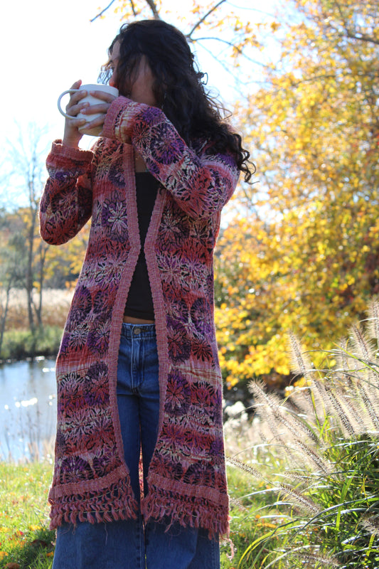 Floral patterned sweater in red and purple with decorative fringe and clasp at the front.