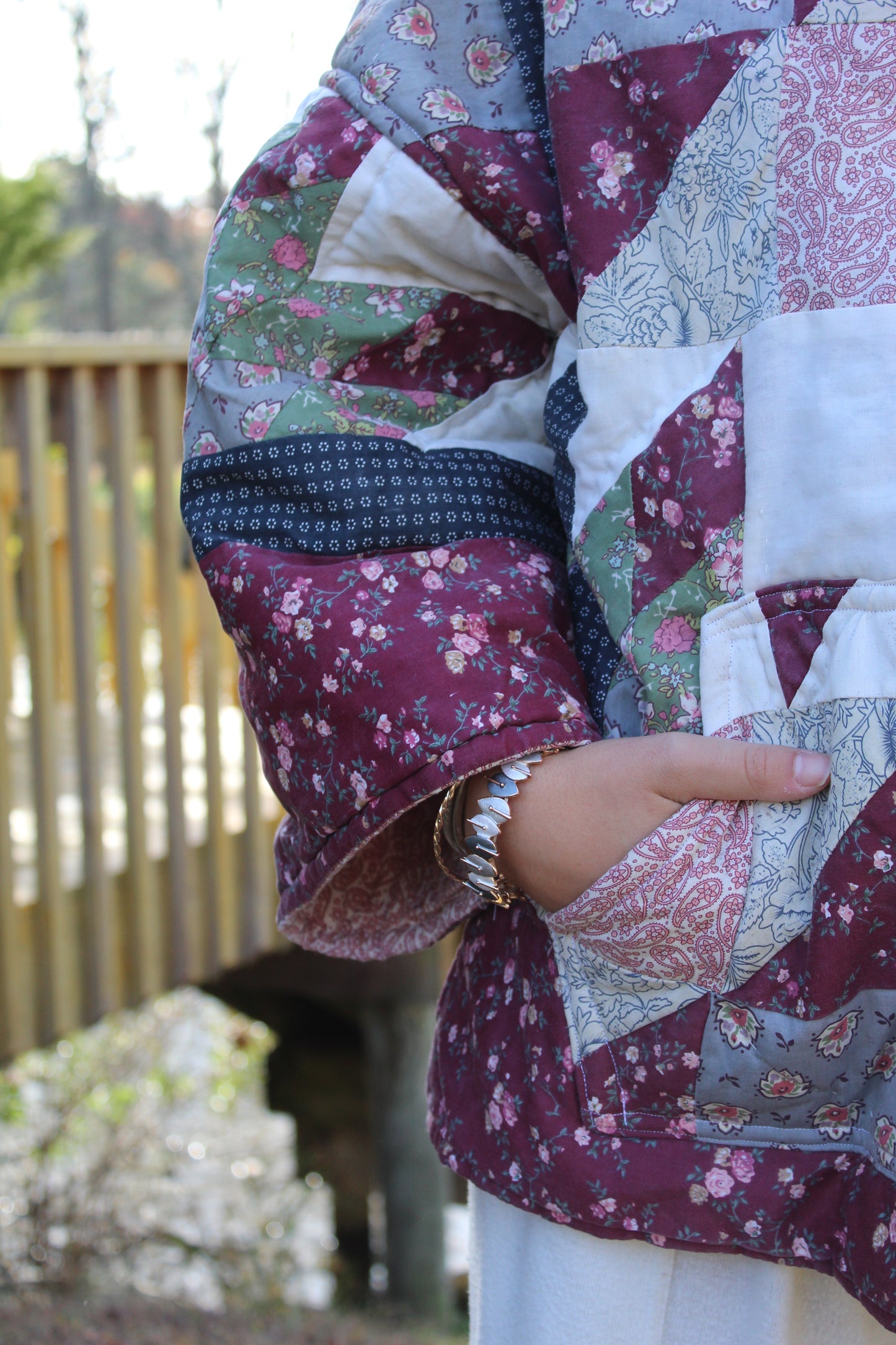 Close-up of quilted handmade hoodie showing dark red and blue stitched patchwork.