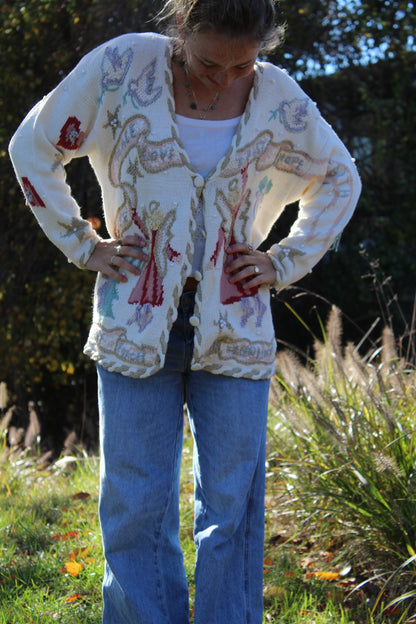 White button-up sweater featuring embroidered angel designs and delicate beaded details on the front.”