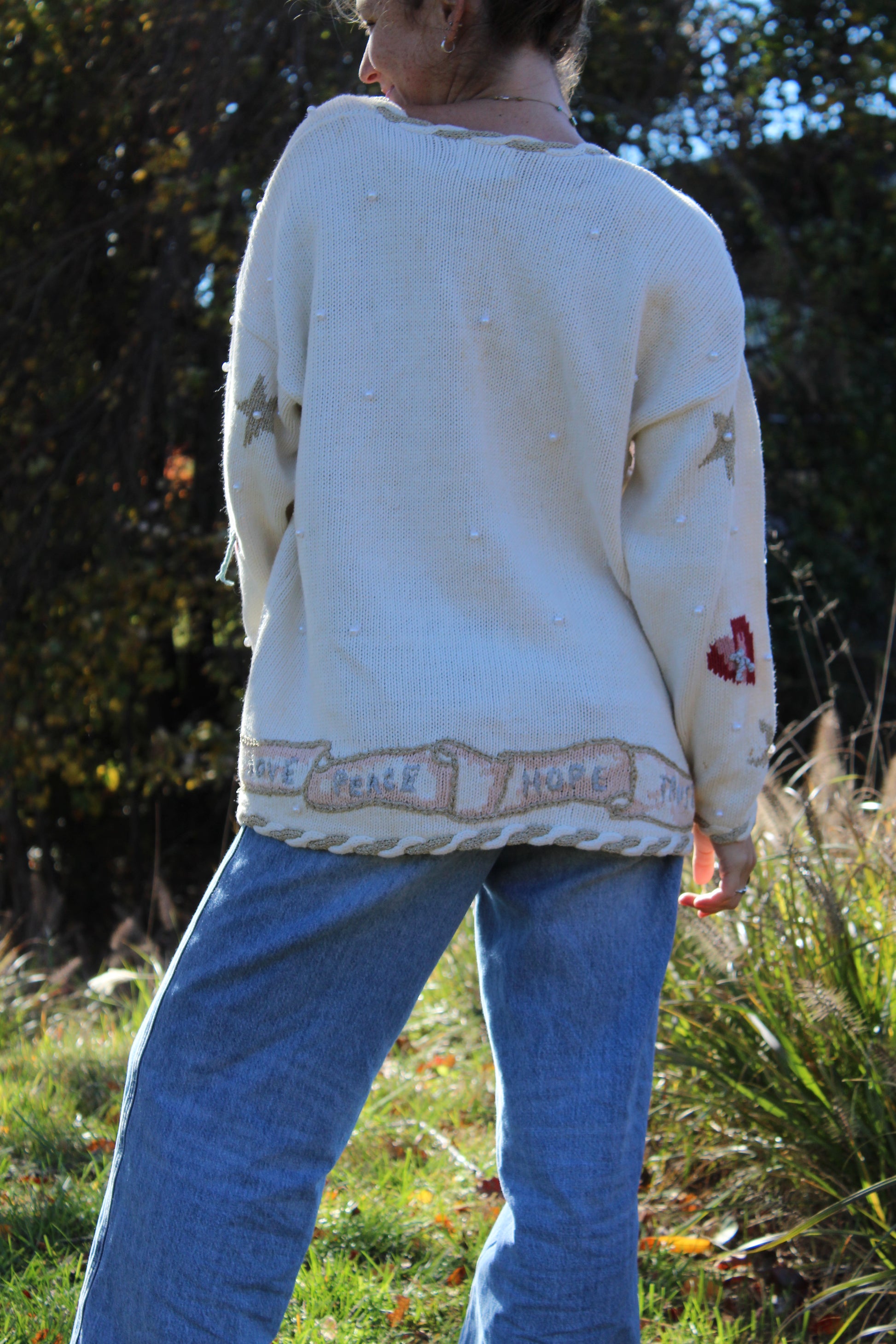 “White vintage button-up knit with ornate angel designs and sparkling beaded embroidery on the front.”