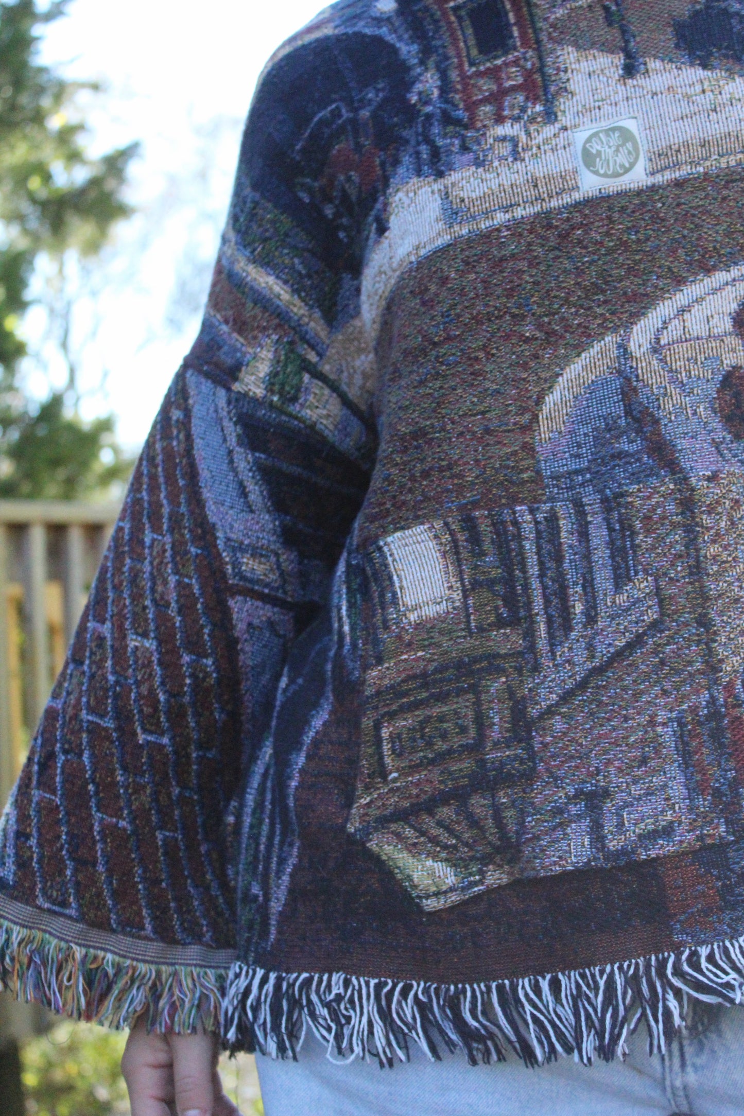 Colorful vintage blanket hoodie with bohemian fringe and ornate woven textures.