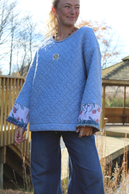 Blue handmade crewneck crafted from a vintage quilt, featuring floral fringe sleeve cuffs.
