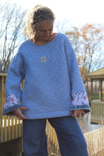 Close-up of floral fringe detail on blue quilted crewneck made from vintage fabric