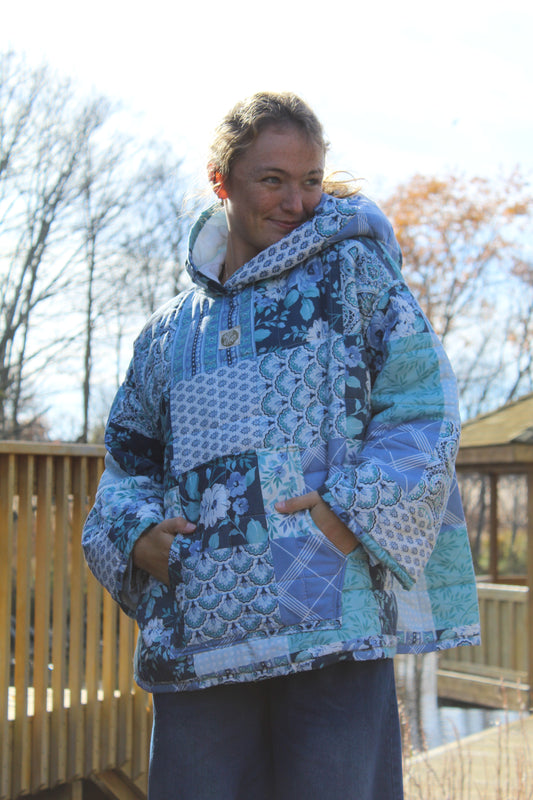 Handmade blue quilted hoodie created from a vintage quilt with floral patchwork patterns.