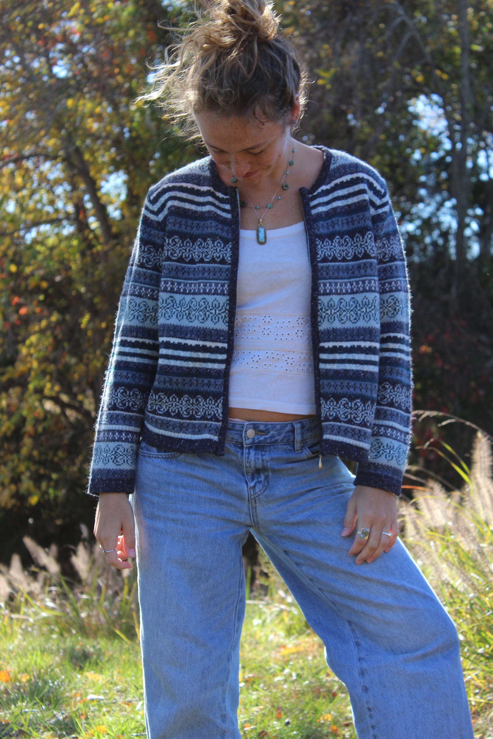 Blue zip-up sweater with geometric-style patterns and ribbed edges.