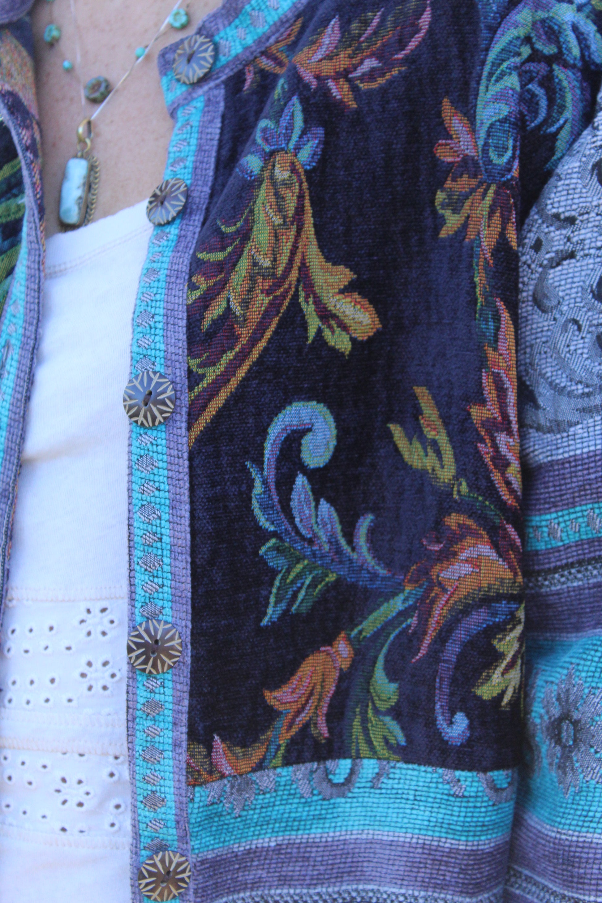 Vintage-inspired blue burlap jacket decorated with floral designs and character-filled buttons.