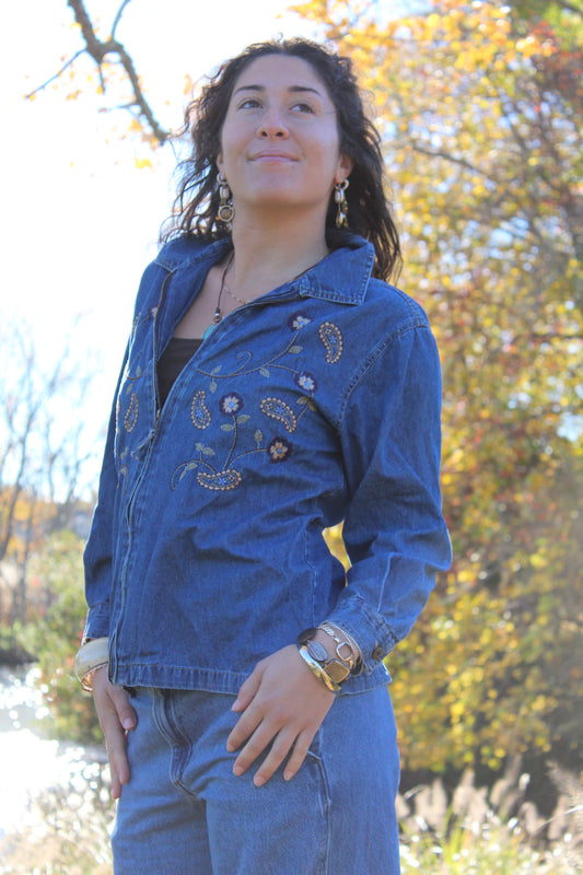 Medium-wash denim zip-up jacket featuring subtle embroidered accents.