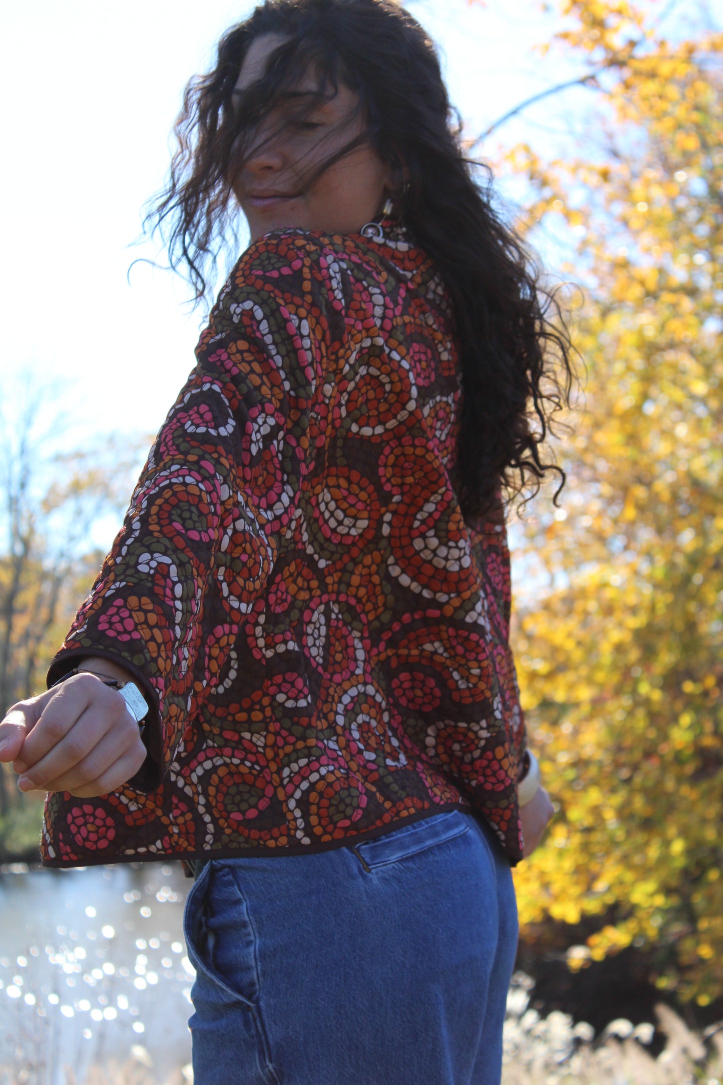 Close-up of a thin quilted button-up with vibrant orange and red polka dots.