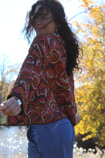 Close-up of a thin quilted button-up with vibrant orange and red polka dots.