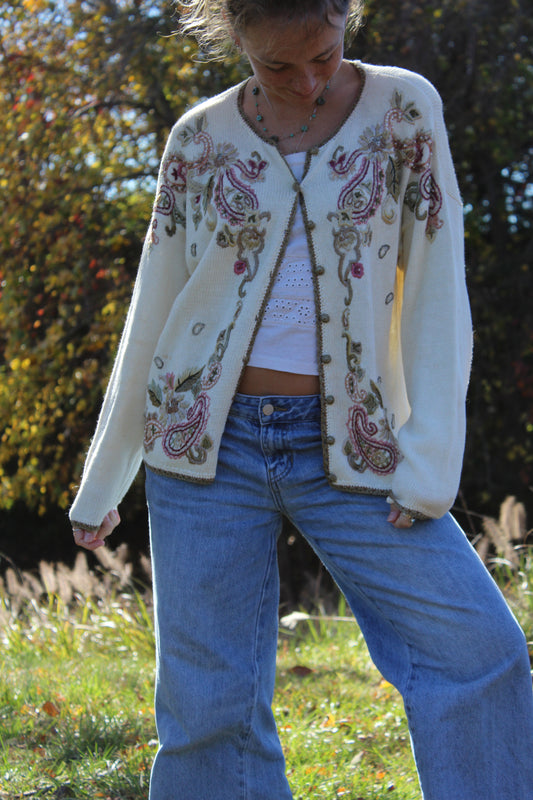 Sweater with floral embroidery, gold trim, and button-up front.