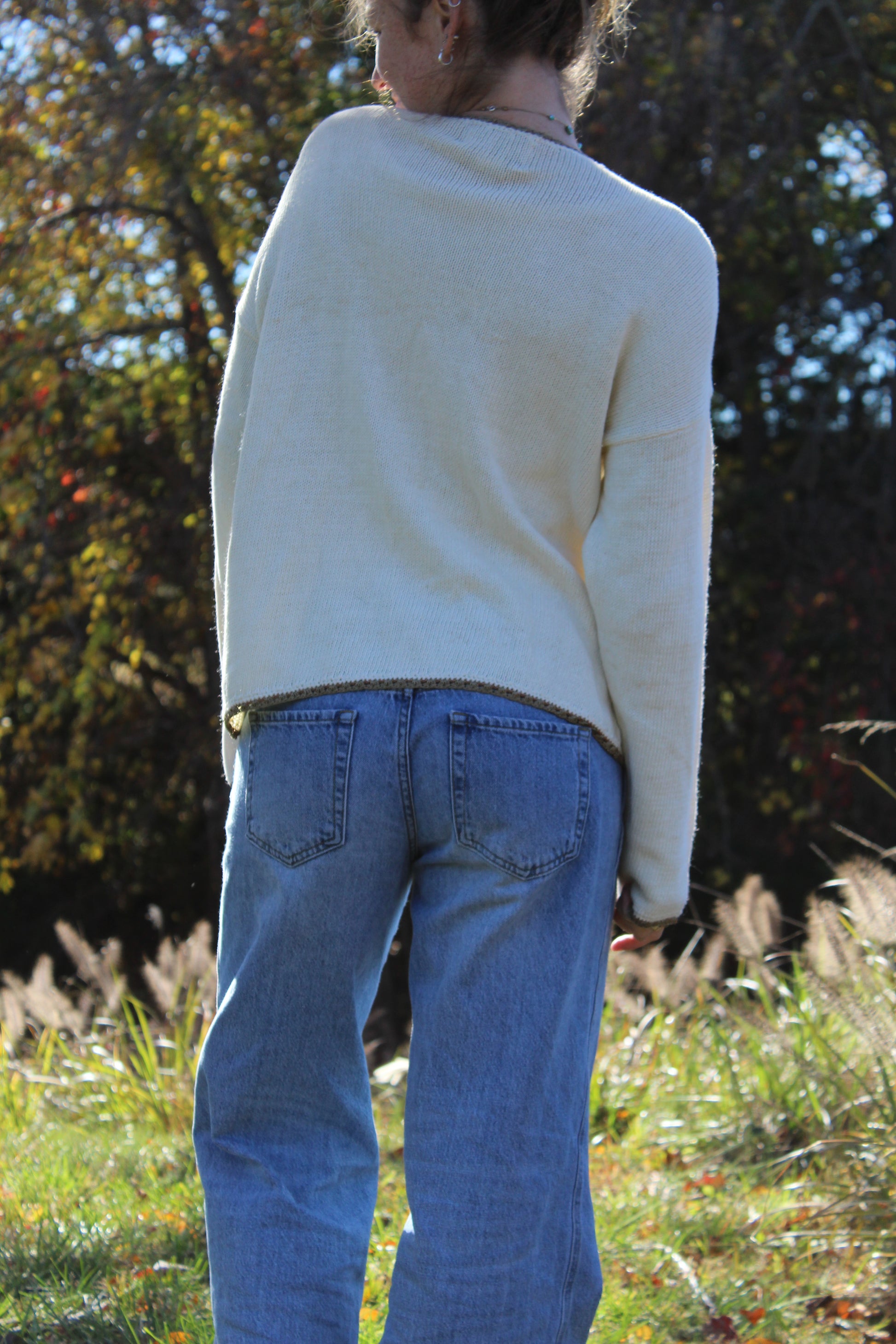 Elegant sweater with floral stitched details, gold trim, and button-up design.