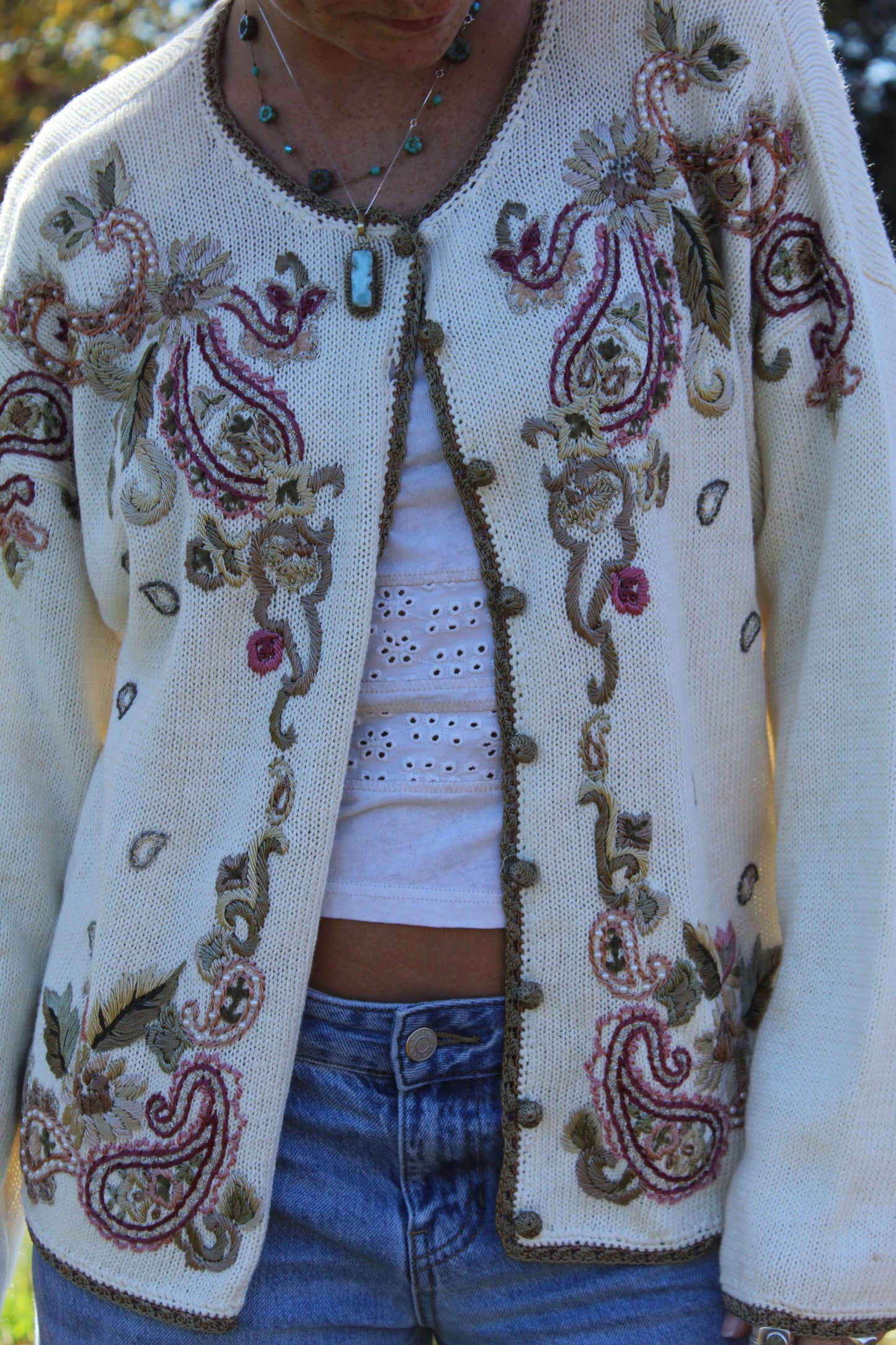 Button-up sweater with intricate floral embroidery and subtle gold trim highlights.