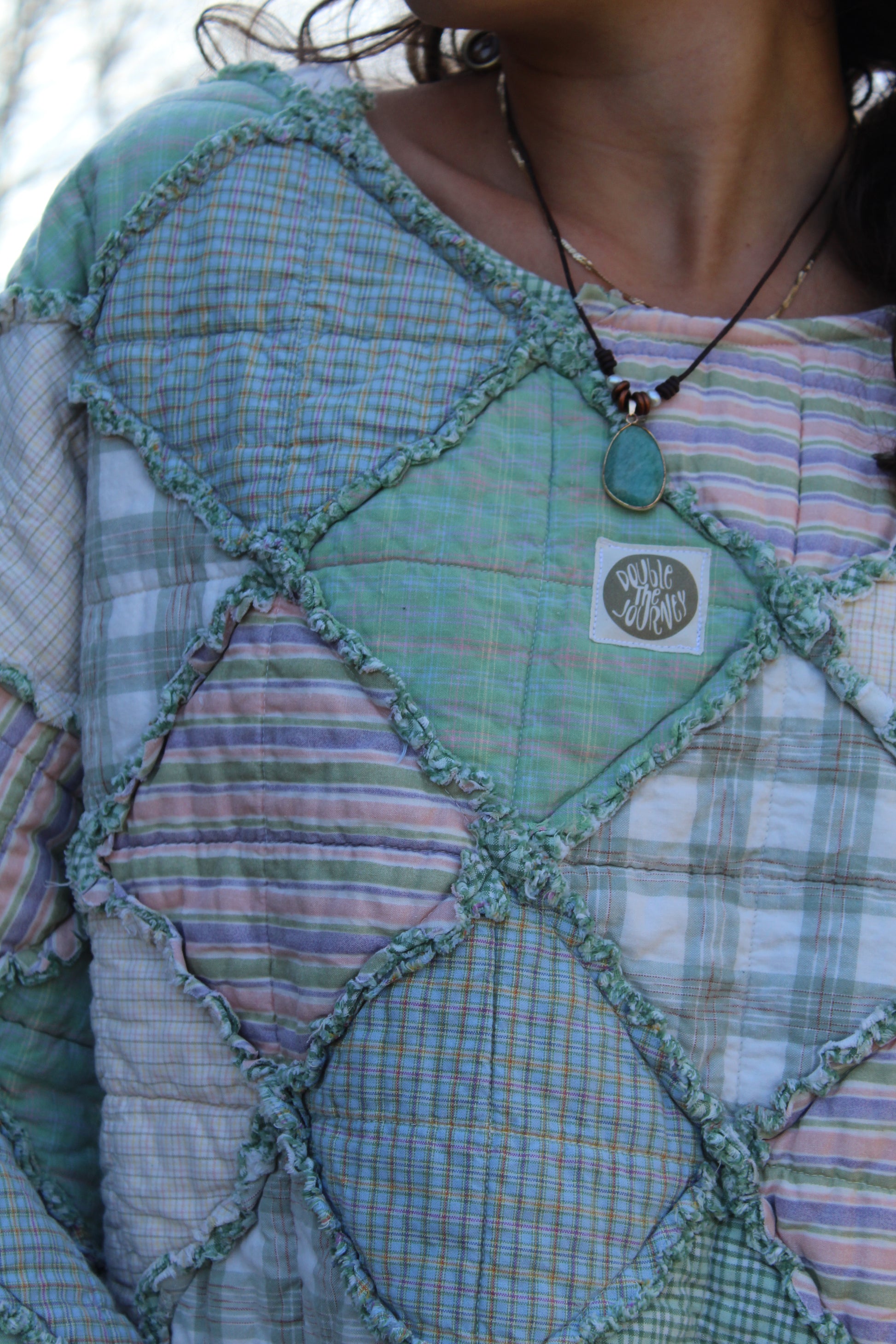 Close-up of green patchwork crewneck showing stitched textures and quilted design.