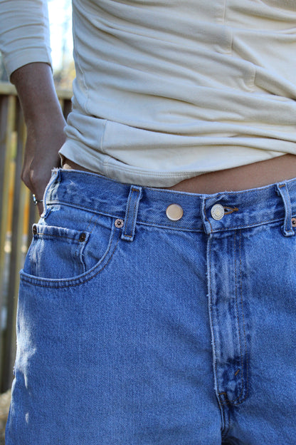 Close-up of a person wearing blue jeans with  buttons