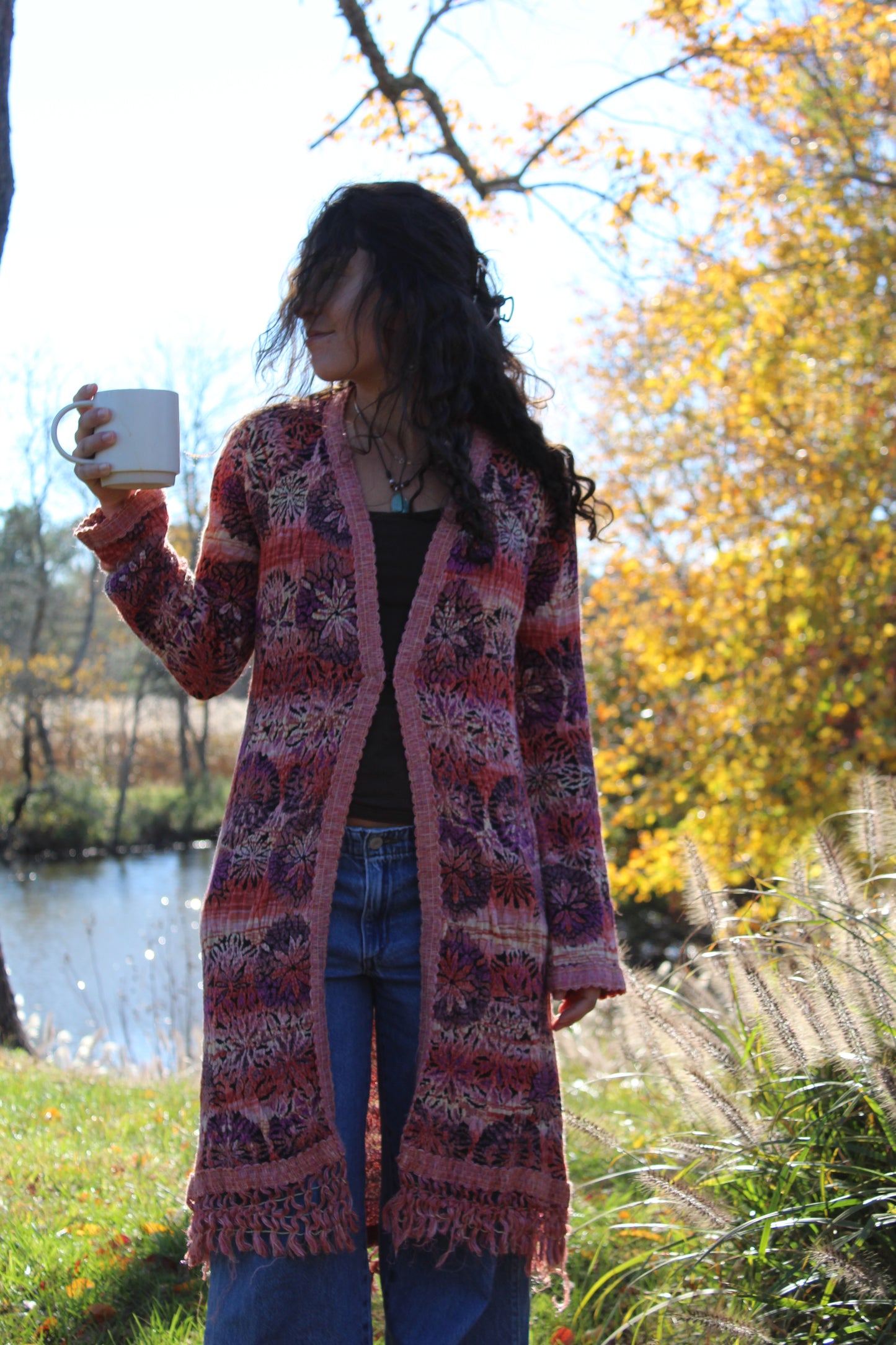 Long red and purple floral sweater with fringe details and a front clasp closure.