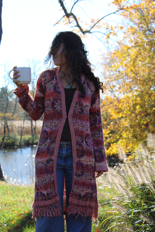Long red and purple floral sweater with fringe details and a front clasp closure.