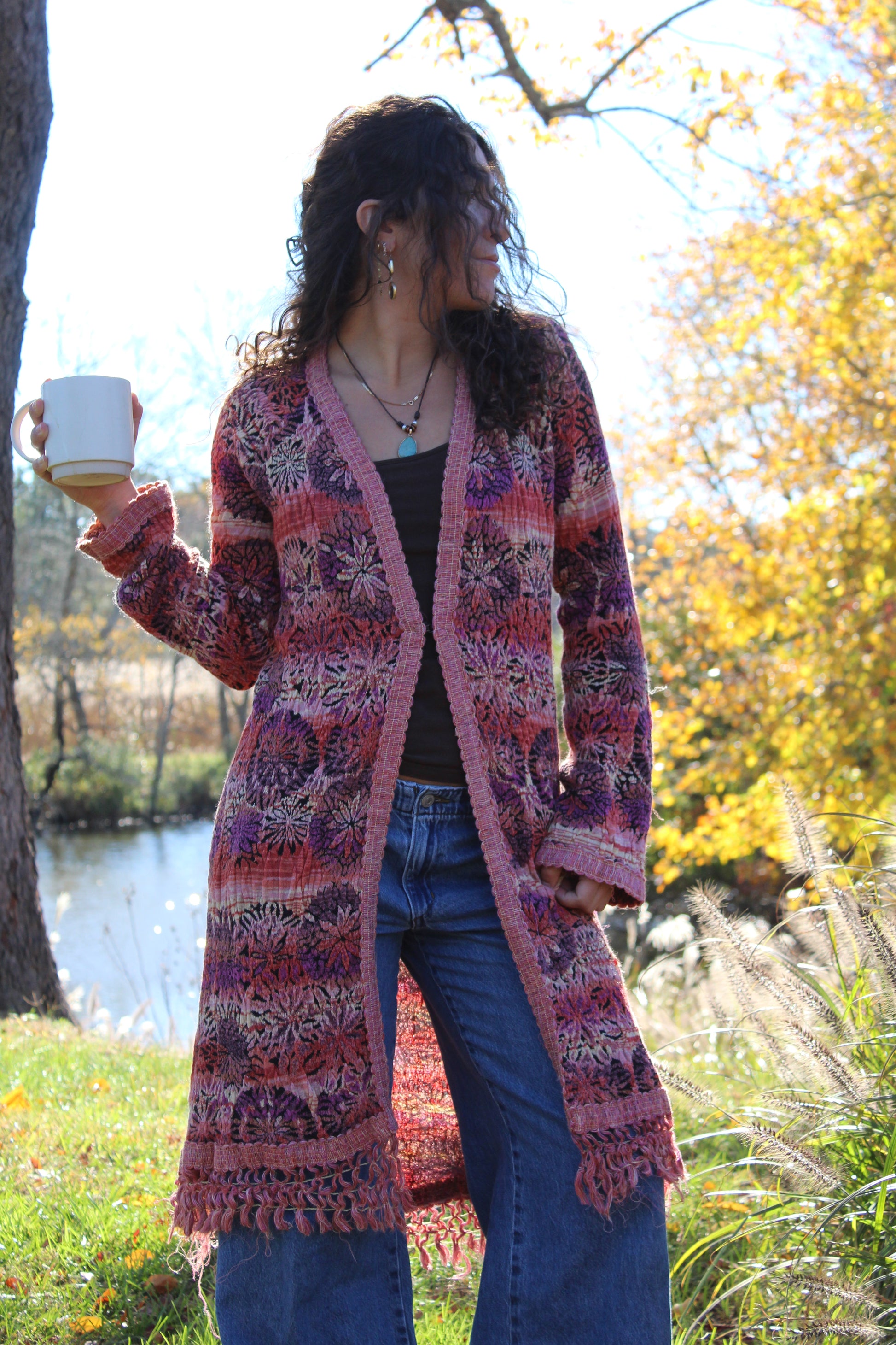Vintage-inspired long sweater featuring red and purple flowers, fringe accents, and front clasp.