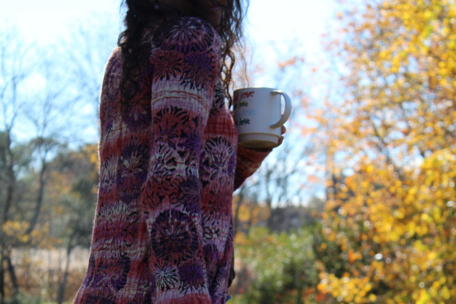 Statement long sweater with red and purple floral design, fringe edges, and front clasp.
