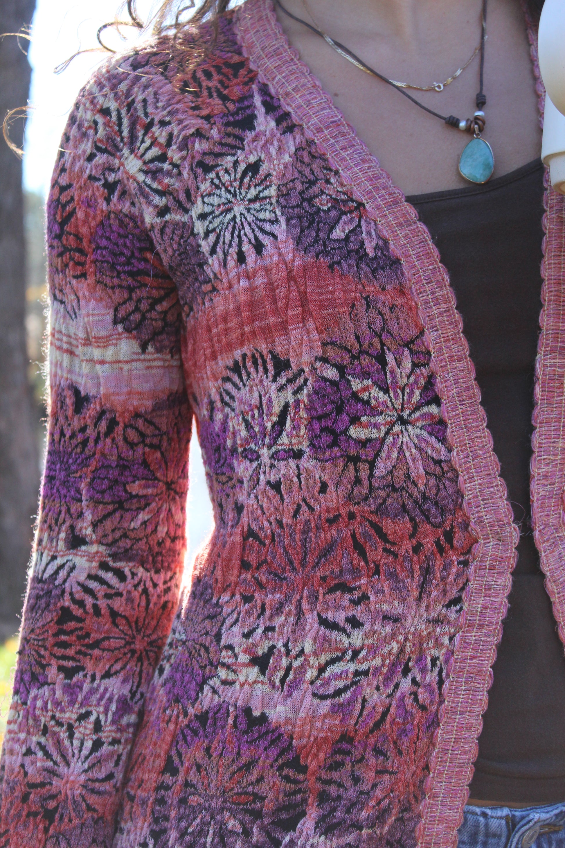 Cozy long floral sweater in red and purple with playful fringe and secure front clasp.