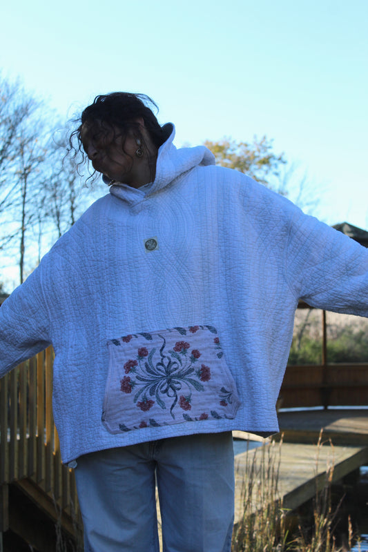 Vintage handmade quilted hoodie with soft blue stripes and a floral front pocket.