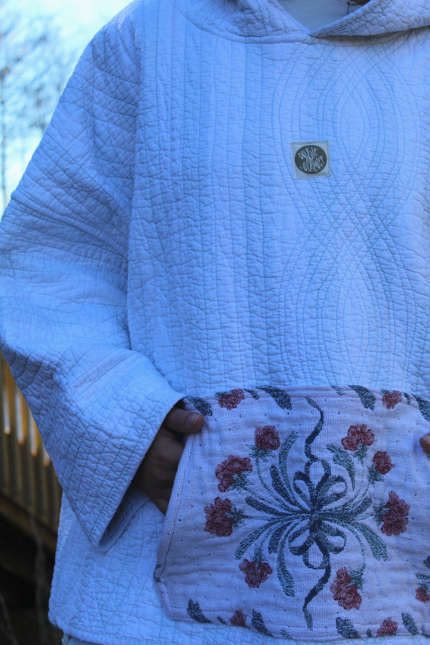 Cozy handmade quilted hoodie with faint blue stripes and a patterned floral pocket.