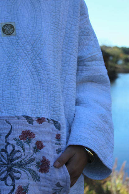 Upcycled quilted hoodie with blue striped panels and a charming floral patch pocket.