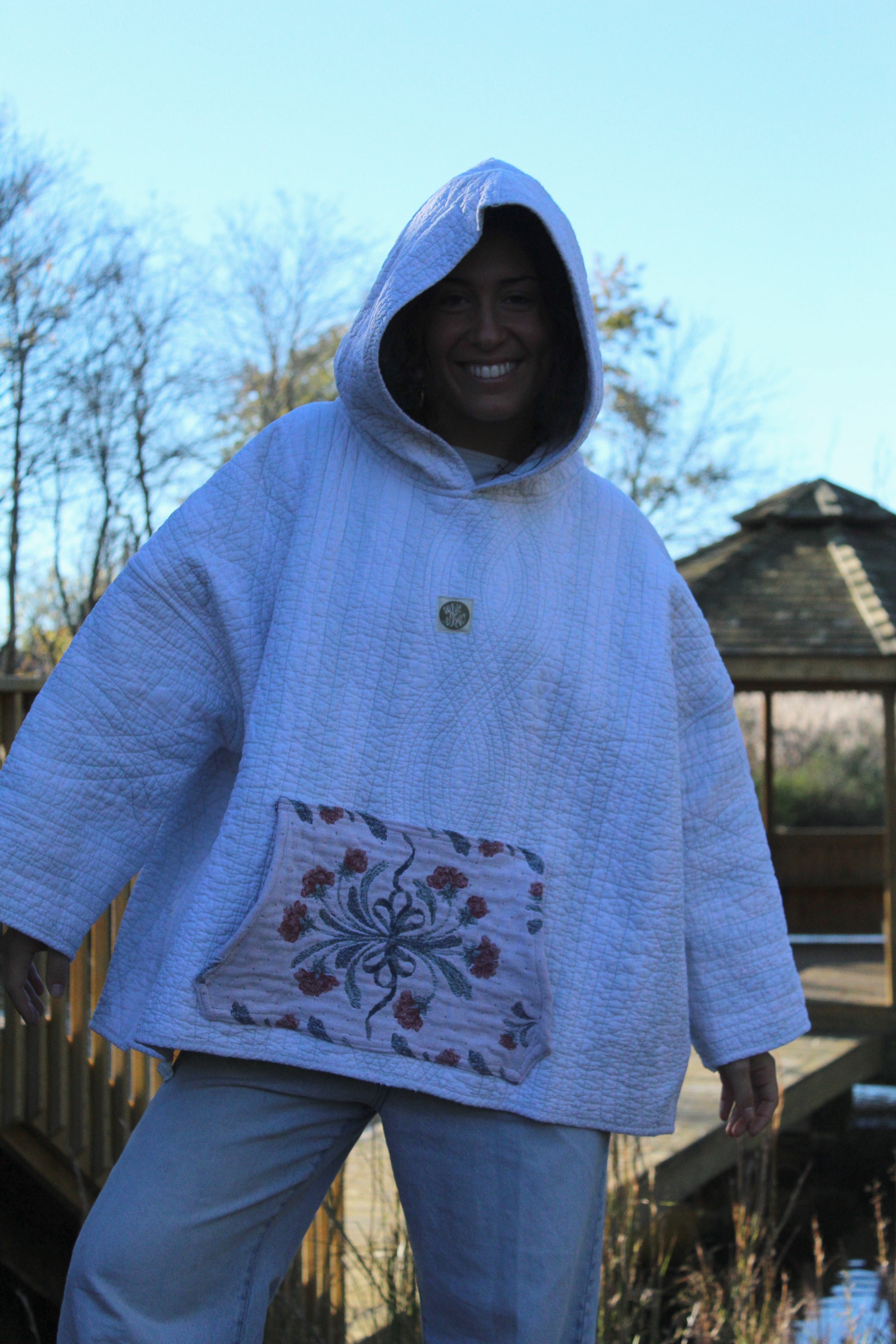 Vintage-inspired quilted hoodie with subtle blue stripe detailing and a small floral pocket.
