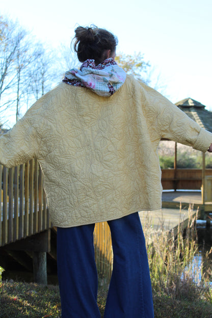 Upcycled yellow hoodie decorated with embroidered flowers and mixed-pattern fabric details