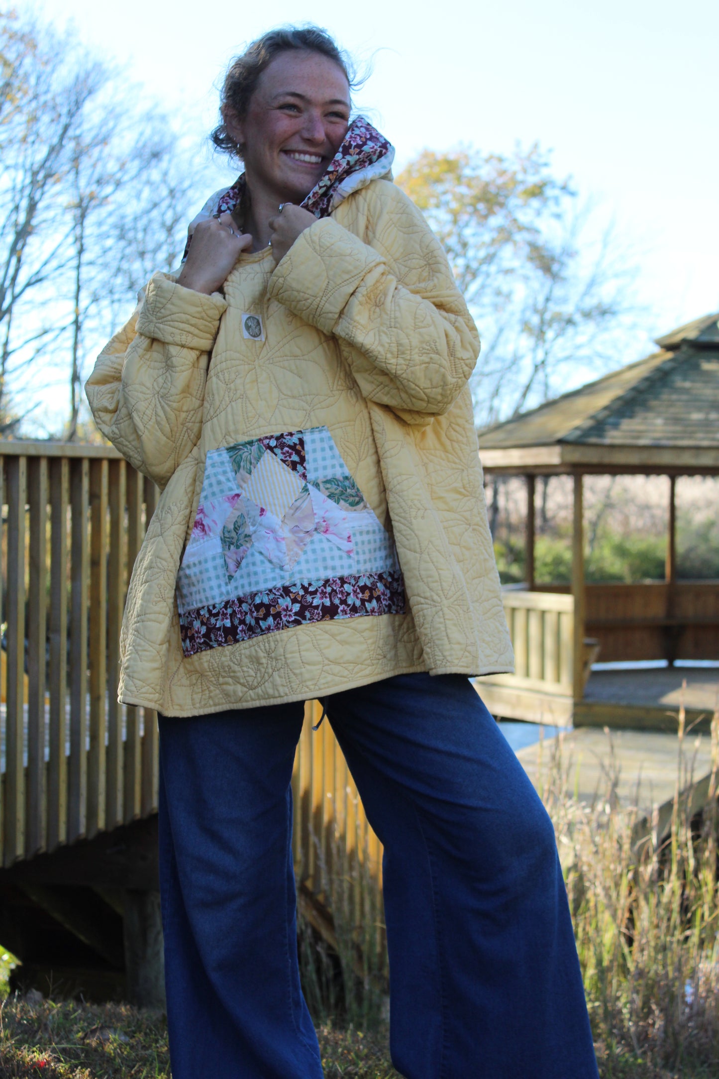 Yellow hoodie with floral embroidery and patterned fabric on the pockets and hood