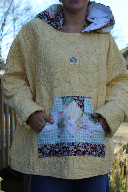 Cozy yellow hoodie featuring detailed floral embroidery and contrasting patterned trim